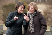 Two women looking at a phone and laughing